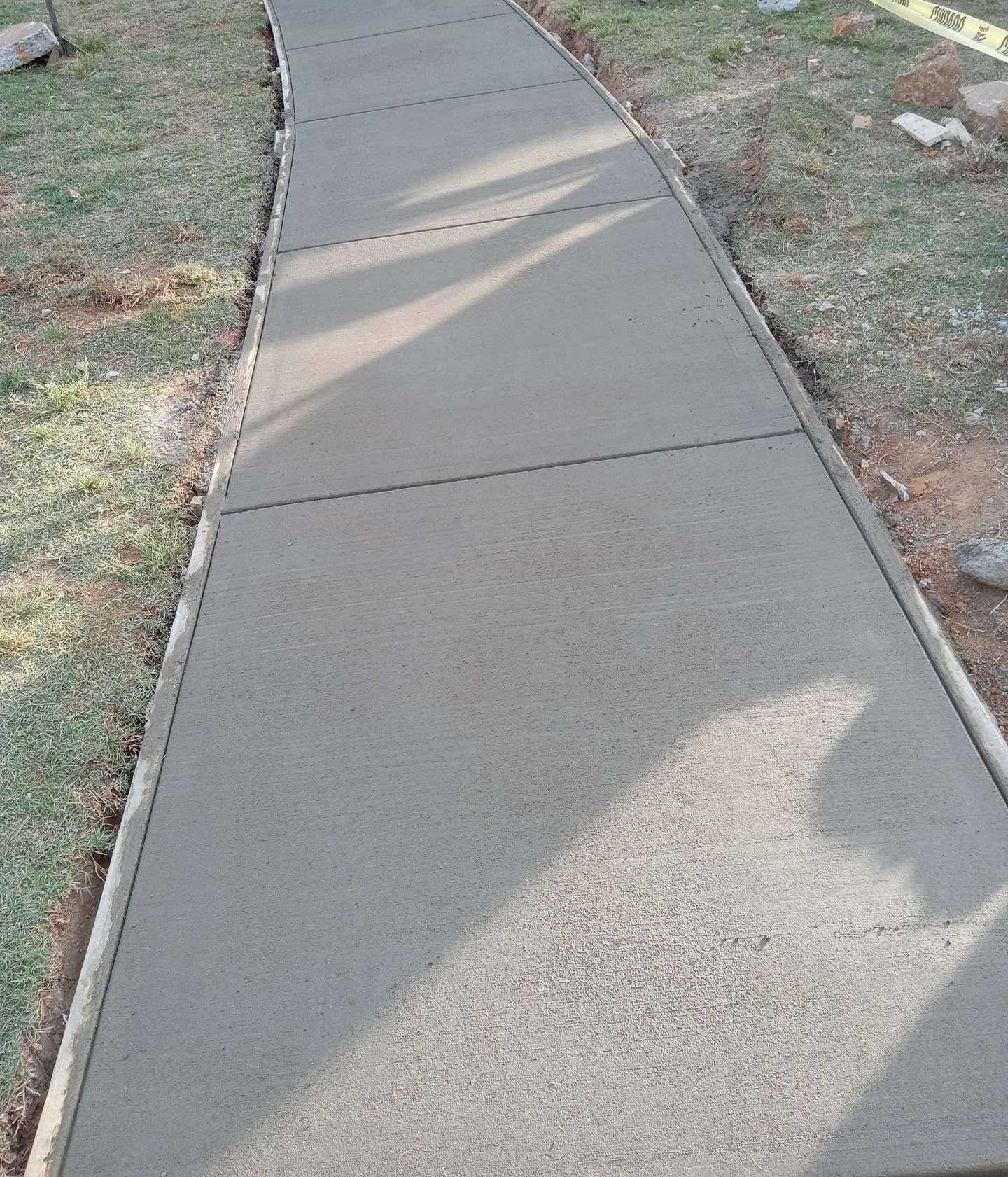 Freshly poured concrete walkway with control joints and form boards along its edges