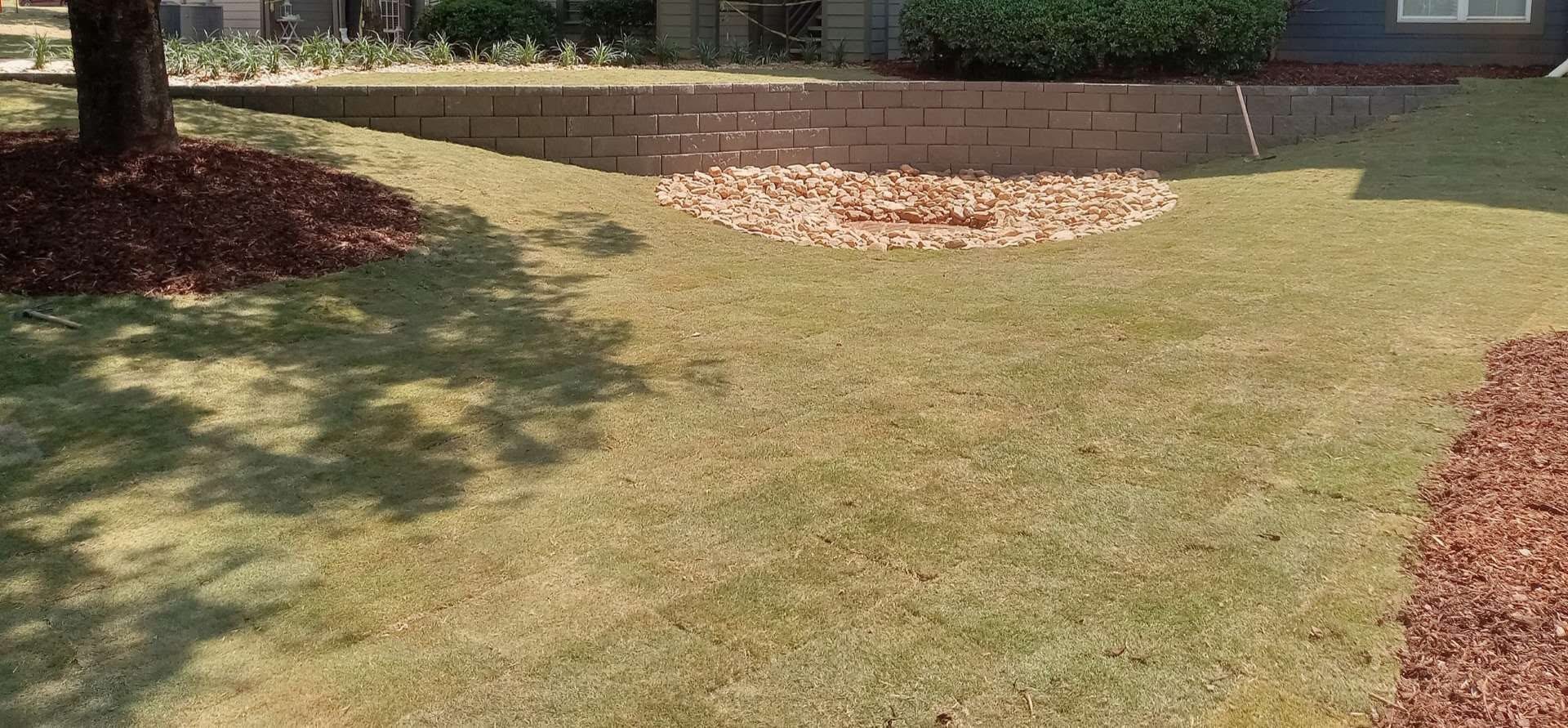Finished block retaining wall above a lawn and decorative stone landscape area